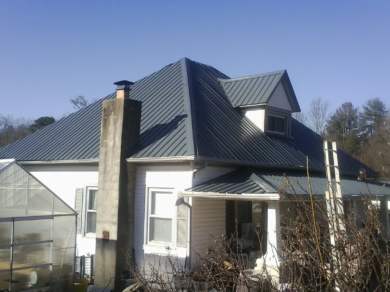 Dark blue standing seam metal roof on a white farmhouse with dormer — Slate & Tile Roof Repair by Roofing Brothers in Ocean Beach