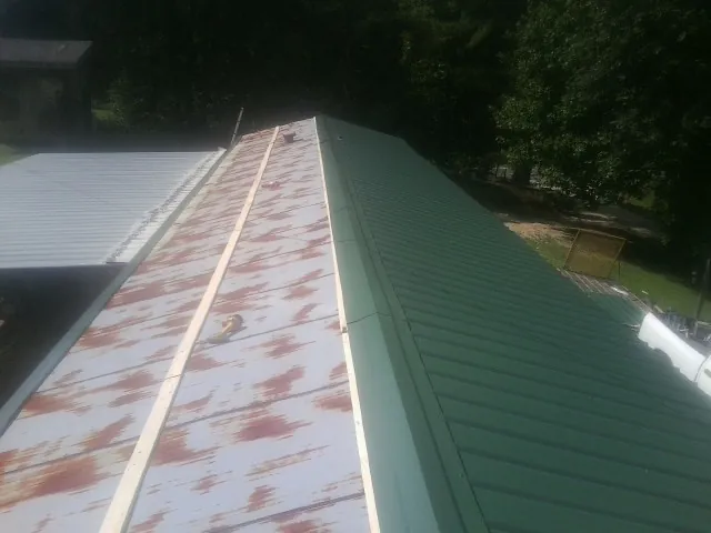Old rusted panels beside newly installed green metal roofing — Wind Damage Roof Repair by Roofing Brothers in Ocean Beach