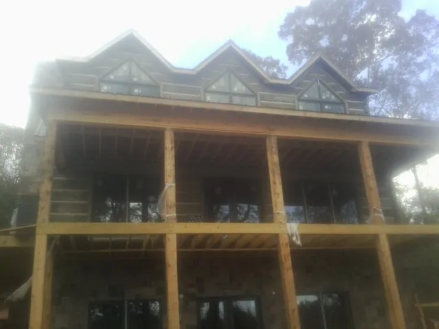 Dormers and porch framing on a large log home under construction — Roof Coating work by our crew in Ocean Beach