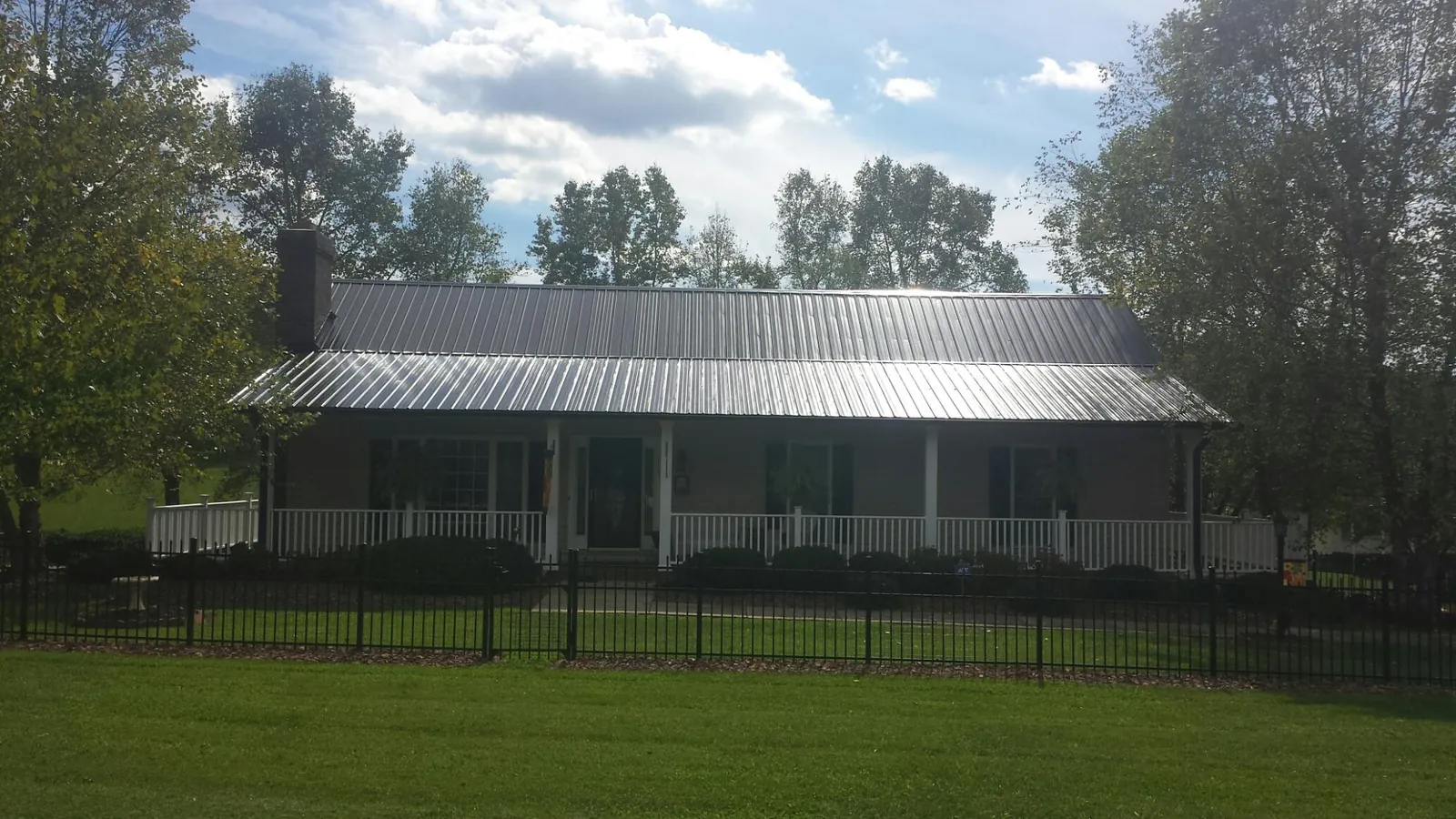 Gray metal roof on a brick ranch with a full width front porch — Gutter Guard Installation work by our crew in Ocean Beach