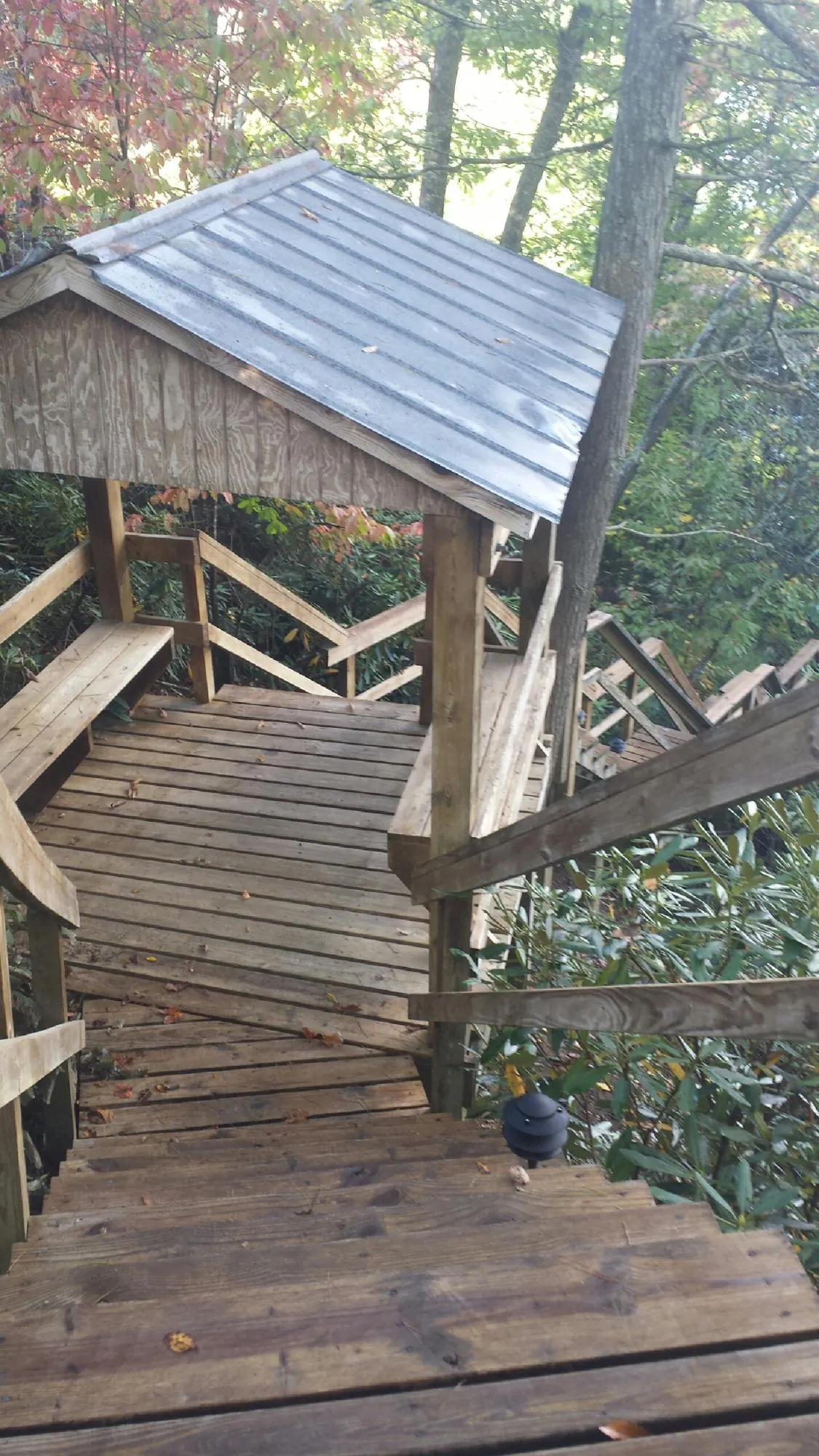 Metal roofed shelter over wooden steps on a wooded walkway — Skylight Repair & Installation work by our crew in Ocean Beach