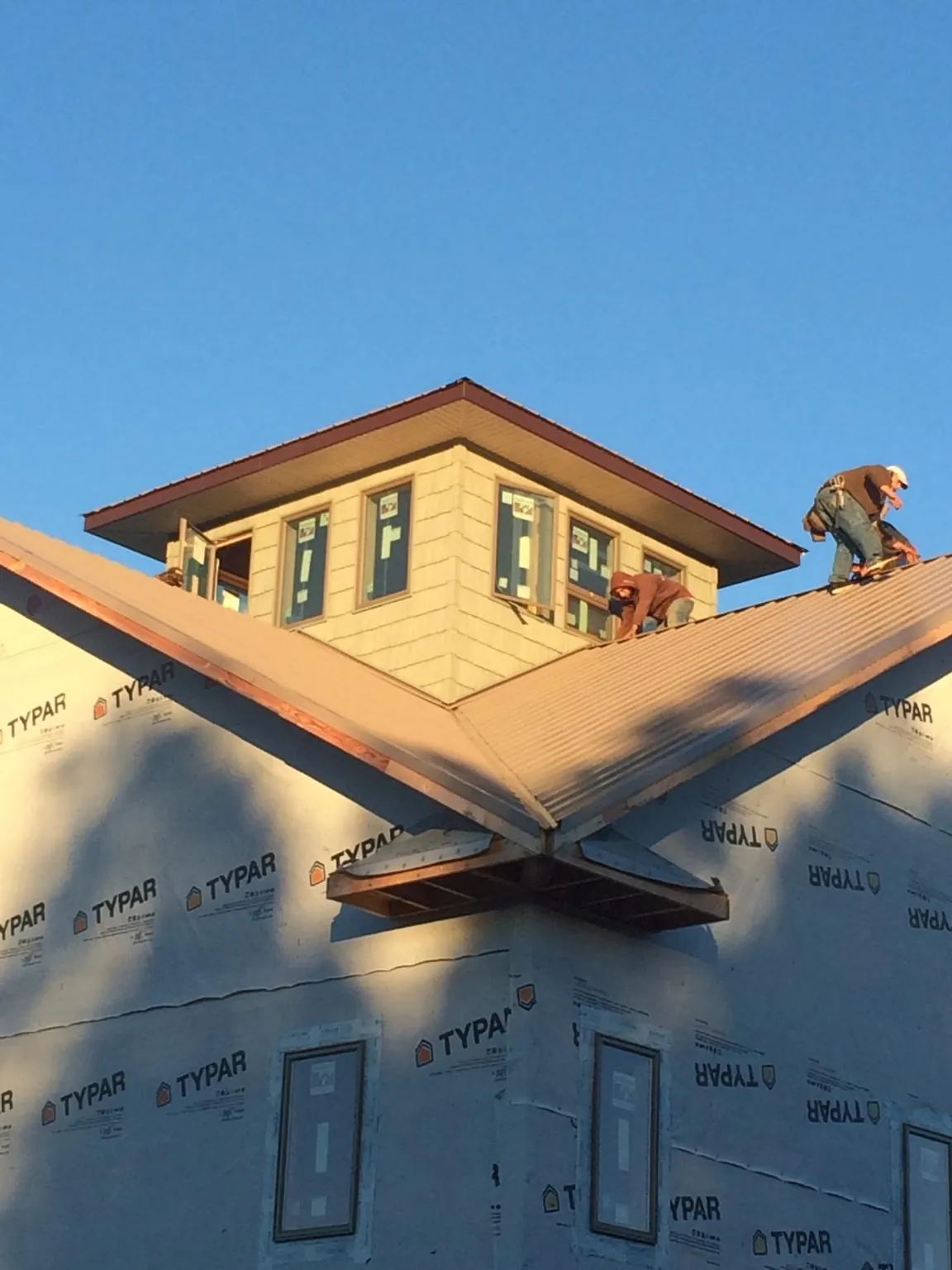 Roofers working around a rooftop cupola on a new metal roof at sunset — Roof Waterproofing in Ocean Beach by Roofing Brothers